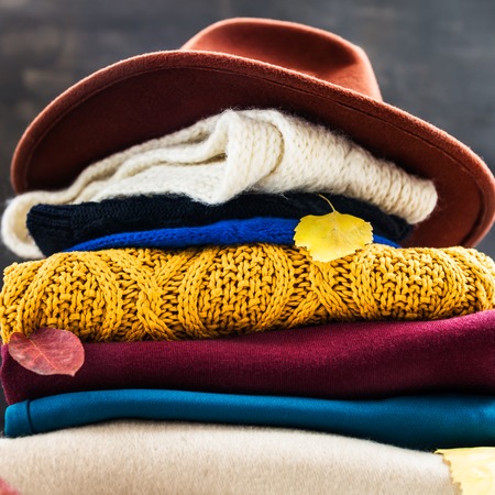 Stack of colorful warm autumn and winter clothes on dark backgroundの写真素材