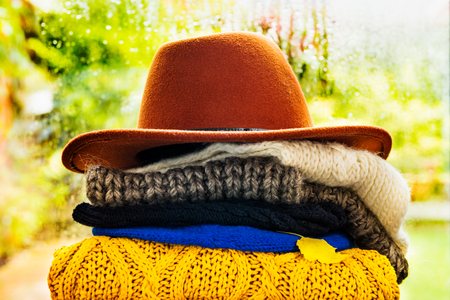 Stack of colorful warm autumn and winter clothes such as scarfs, sweaters, hatsの写真素材