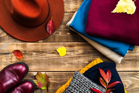 Stack of colorful warm autumn and winter clothes, top view, wooden rustic backgroundの写真素材