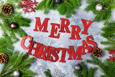 Christmas Frame made from Xmas Tree Branches, Baubles, and Red Letters Merry Christmas on the Grey Background, Top View, Flat layの写真素材