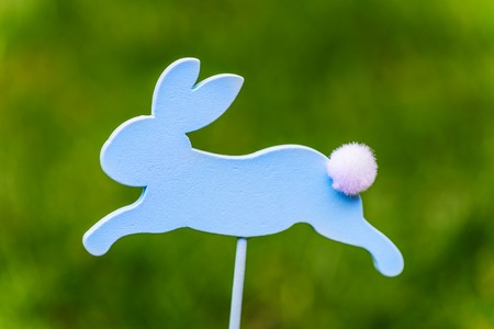 Wooden Bunny as a Symbol of Easter, on Dark Green Natural Background
