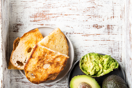 Pieces of toasted white sourdough bread and ripe avocado on rustic backgroundの写真素材