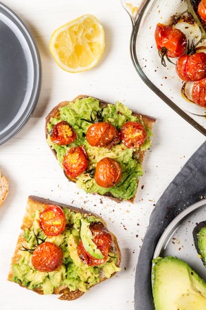 Healthy snack from white sourdough bread, such as avocado and roasted tomatoes toasts