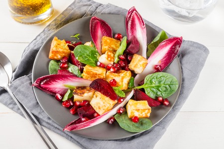 Pomegranate, beetroot, red chicory, spinach, mint and halloumi salad light backgroundの写真素材