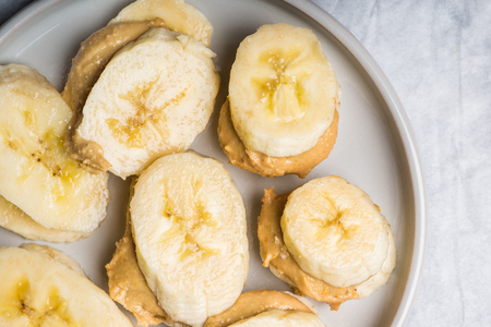 Light Healthy Snack made from Banana Slices and Cashew Butter, on Grey Backgroundの写真素材