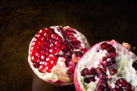 Ripe Open Pomegranate on dark rustic background