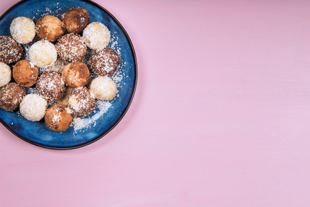 Various Homemade Raw Vegan Truffles or Energy Balls, such as Coconut and Lemon, Almond and Cacao, Dark Chocolate and Hazelnut Butter on Blue Plate and Pink Backgroundの写真素材