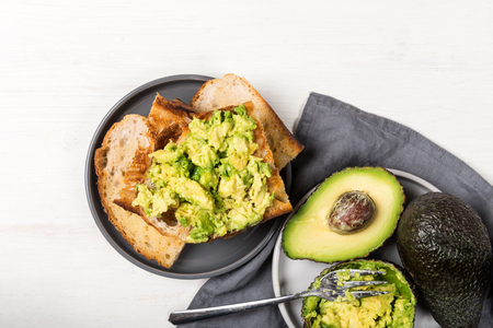Healthy snack of avocado toasts from sourdough bread on light wooden backgroundの写真素材