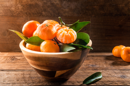 Delicious and beautiful mini Tangerines with leaves in the wooden bowlの写真素材