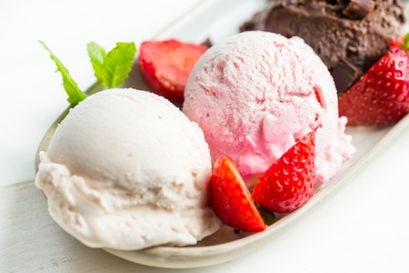 Selection of different ice cream scoops such as mint, chocolate and strawberry on the oval plate