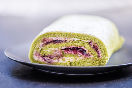 A delicate roulade of Matcha tea sponge, filled with fruity Morello cherry compote and creamの写真素材