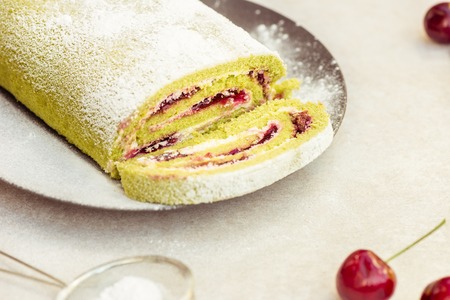 A delicate roulade of Matcha tea sponge, filled with fruity Morello cherry compote and creamの写真素材