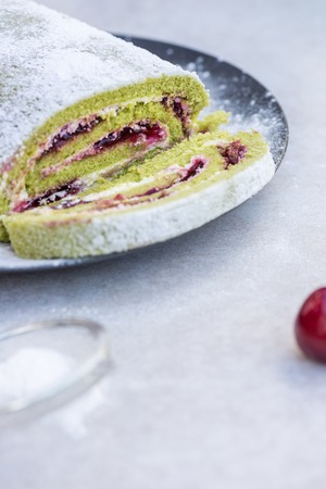 A delicate roulade of Matcha tea sponge, filled with fruity Morello cherry compote and creamの写真素材