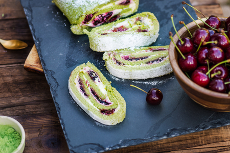 A delicate roulade of Matcha tea sponge, filled with fruity Morello cherry compote and creamの写真素材