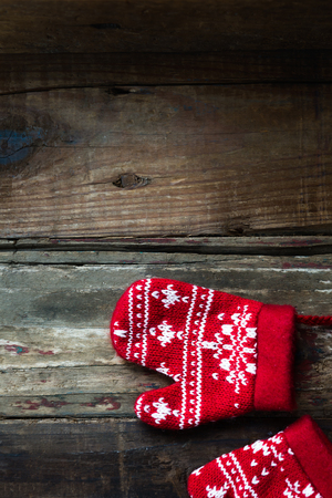 Christmas Red Knitted Mittens with Snowflake Motives on rustic wooden backgroundの写真素材