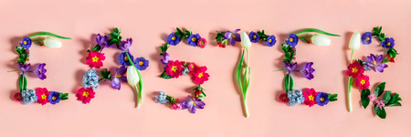 Easter minimal concept. Banner with word Easter made from spring flowers on the pink backgroundの写真素材