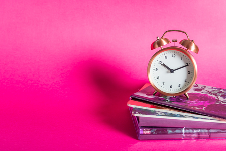 Different Notebooks and alarm clock on bright pink background. Idea of Girly Desk table or Office settings. Back to school conceptの写真素材