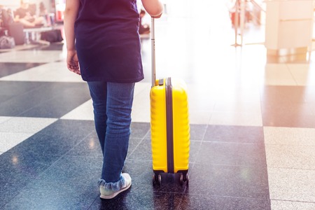 Girl is in the airport with bright and stylish cabin size suitcase as holiday conceptの写真素材