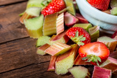 Close up of Pieces of Raw and Freshly Cut Rhubarb and Strawberries on Dark Rustic Backgroundの写真素材