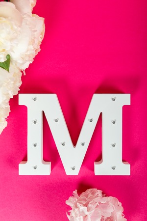 Wooden decorative letter M on pink backgroundの写真素材