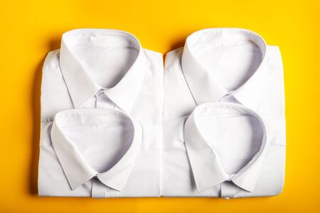 Flat lay with back to school concept, school uniform such as white shirts on bright yellow backgroundの写真素材