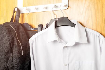 Back to school concept, school uniform such as white shirts, trousers and jumper hanging on the doorの写真素材