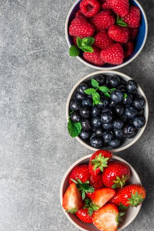 Fresh summer berries in the bowls. Blueberries, strawberries, raspberries shoot from the topの写真素材