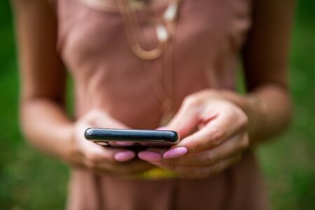 Beautiful slim lady with perfect manicure is using her smartphoneの写真素材
