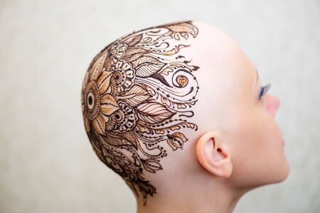 Drawing process of henna mehndi tattoo on womans bald headの写真素材