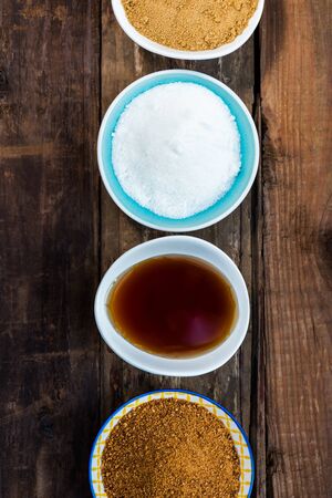 Different Kinds of Sugar and Sweeteners in the Bowls, such as coconut, pure cane, icing, maple syrup, dark brown soft sugar, honey, demerara cubesの写真素材