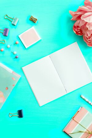 Empty Notebook for writing Dreams and Ideas, with different Stationery, and Big Pink Peony flowers laying on Green background. Top View. Idea of Girly Office settings. Flat lay style.の写真素材