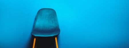 Modern Blue Velour Chair on wooden legs, blue background, banner size, copy spaceの写真素材