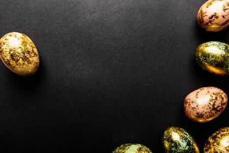 Natural Golden Speckled Easter Eggs of pastel colors on black background. Happy Easter card concept, minimalistic design, copy spaceの写真素材