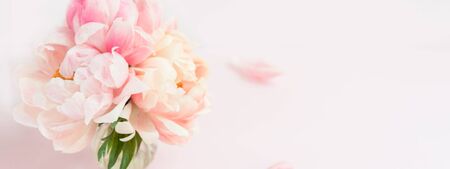 Fresh bunch of pink peonies and roses in a vase on pink background. Card concept, pastel colors,...