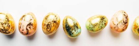 Natural Golden Speckled Easter Eggs of pastel colors on white background. Happy Easter card concept, minimalistic design, copy space, banner sizeの写真素材