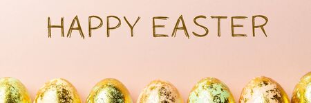 Happy Easter text. Natural Golden Speckled Easter Eggs of pastel colors on pink background. Happy Easter card concept, minimalistic design, banner sizeの写真素材