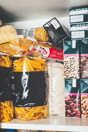 London, UK: March 18, 2020: Cupboard shelves fool of food provision, such as pasta, rice, porridge, canned tuna, beans and more. Panic buying to survive Coronavirus COVID 19 pandemic during lock down.のeditorial素材