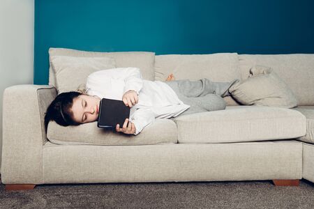School age girl is home schooling using e reader during self isolation at her bedroom, online...
