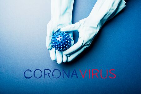 Word Coronavirus. Abstract virus strain model of COVID-19 or Coronavirus in hands in gloves. Protect yourself, stay home concept. Blue backgroundの写真素材