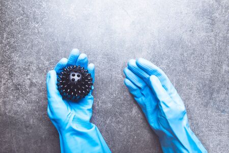 One hand in gloves is holding an abstract virus strain model of COVID-19 or Coronavirus. Protect yourself, stay home. Dark grey backgroundの写真素材
