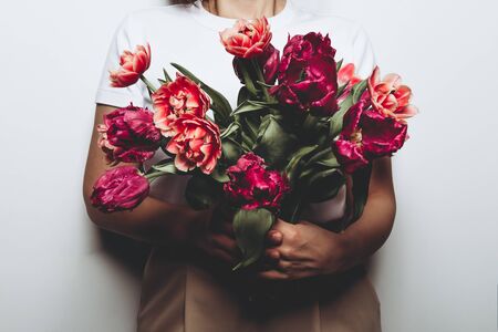 Beautiful Bunch of Peony Style Tulips in the hands of young woman, spring holiday concept, copy space, present for mothers day from kidsの写真素材