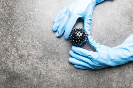 Abstract virus strain model of COVID-19 or Coronavirus in hands in gloves. Protect yourself, stay home concept. Dark grey backgroundの写真素材