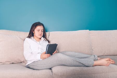School age girl is home schooling using e reader during self isolation at the living room on the...