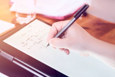 Young university professor is doing online lecture for his students from home during lockdown. He is using 2 in 1 convertible laptop and is writing math formulas with stylus penの写真素材