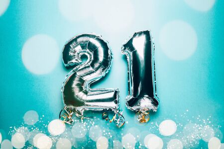 Silver Number Balloons 21 on green background with bokeh lights. Holiday Party Decoration or postcard concept with top viewの写真素材