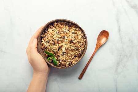 Roasted healthy homemade granola with Gluten Free Rolled oats or porridge oats, variety of chopped nuts and seeds, and maple syrup. Portion of granola in coconut bowlの写真素材