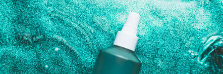 Mat glass bottle of body oil on green water background, glass cosmetics in water, banner size, top viewの写真素材