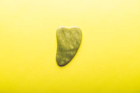 Gua sha stone for beauty facial massage therapy on yellow backgroundの写真素材