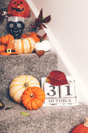 Different types of pumpkins and decorations on stairs indoor. New Normal or Halloween during pandemic at home concept. Stay home, be safe.の写真素材