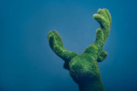 Head of Green Deer with antlers, Christmas or New Year decoration on the wall. Minimal winter...